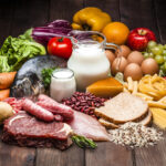 Large group of different types of food like carbohydrates, protein and dietary fiber shot on rustic wooden table. Food included in the composition are dairy products, sausages, minced meat, fish, bread, pasta, beans, fruits and vegetables. DSRL studio photo taken with Canon EOS 5D Mk II and Canon EF 70-200mm f/2.8L IS II USM Telephoto Zoom Lens